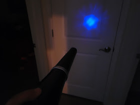 A big blue terahertz wand model being pointed at a door and showing light and frequencies