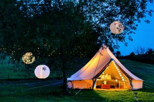 Photo of a large bell tent decorated with a bed and tables. A glamiping experience.