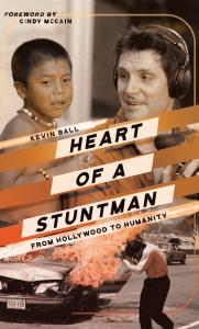 Heart of a Stuntman front cover showing the author in the field with a child and doing a stunt for a TV show