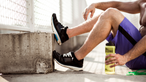 Man resting his leg on wall after muscle strain recovery with Irvine personal trainers