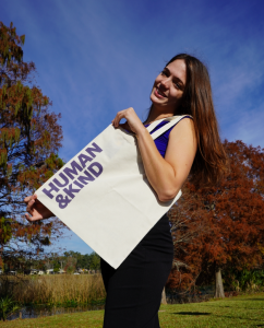 IDEAS For Us Education Coordinator, Kellie, posing with  one of We Are Kind’s newest tote bags. This tote will be  raffled off to members this January.