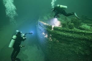 Divers underwater looking at sunken vessel