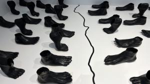 Installation view of 101 larger-than-life-scale ceramic feet arranged on either side of the border at “Ebb/Flow,” an exhibition on view at the Weisman Art Museum, Minneapolis