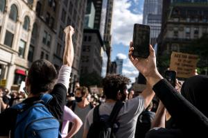Image of people marching in the streets holding devices in the air.