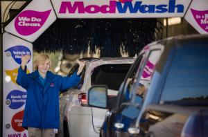 Car wash employee guides guests into wash tunnel