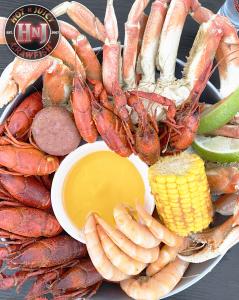 Photo of crawfish, snow crab legs, and shrimp, surrounding a bowl of melted butter