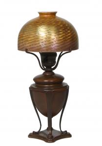 Circa 1910 Tiffany Studios bronze and favrile lamp, 15 inches tall, with a 7-inch diameter shade engraved “L.C.T. Favrile”, stamped with Tiffany Glass and Decorating logo (est. $3,000-$5,000).