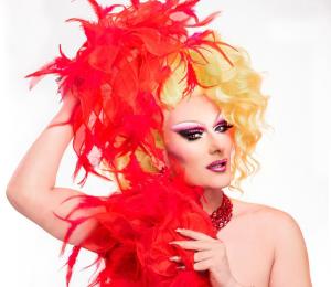 Woman with blond hair, wearing a red outfit with feathers.