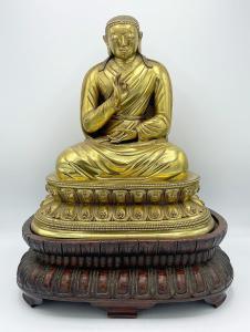 Rare and important gilt bronze Tibetan Buddha, 13 inches tall on on a carved 5-inch-tall stand, showing a serene-faced figure wearing a draped robe, posed in quiet contemplation ($200,000).
