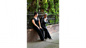 two women leaning on a wall share a laugh