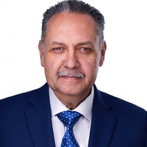 Armando Contreras is a middled-aged man. He is wearing a suit and tie in this headshot photo.