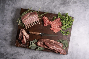 STEELPORT 6" Boning Knife surrounded by various premium cuts of meat and herbs on a cutting board