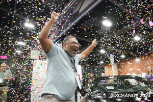A man jumping in the air, in a room filled with confetti after winning a brand new car