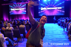 a man is taking a selfie in front of a blue and purple stage
