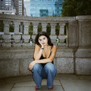 Adeline V. Lopez crouches in front of a wall and looks at the camera