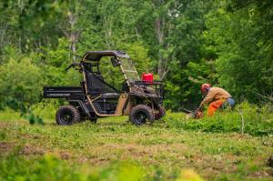 Man cutting logs and using his UTV for work.