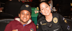 woman Goodyear police officer sitting with young black boy at an event