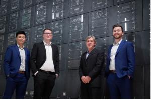 Four men stand in front of wall.