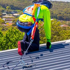 Heartland worker safely tied off at edge of roof
