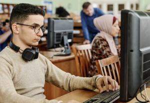 Man using a computer beside other students.