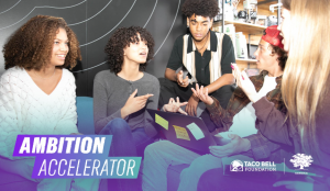 The image depicts a group of young people collaborating together on their community impact initiatives.