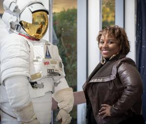 Dr. Camille Wardrop Alleyne standing next to NASA spacesuit shocase at NASA space center