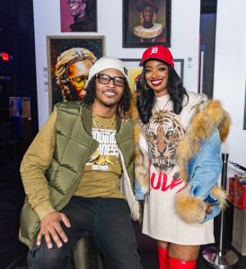 T.I. is a man, wearing glasses sitting in chair posing with Arian, a woman standing alongside.