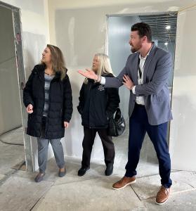 Iliana Montiel, Assistant Director of Health Services; Lee Ann Wander, CEO; and John R. Reeves III, Health Administrator stand in unfinished room, looking at construction progress.