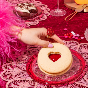 A person's hand holding a Jammy Heart cookie from Crumbl