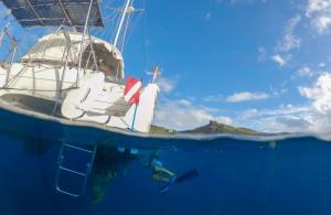 : Diver performing underwater maintenance under a sailboat using the BLU3 Nomad system, showcasing its compact design and effectiveness for boat owners needing easy access to hull cleaning and inspections.