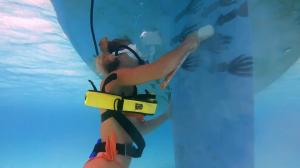 Diver cleaning the hull of a boat using the BLU3 Nomad battery-powered dive system, showcasing its portability and effectiveness for underwater maintenance tasks.