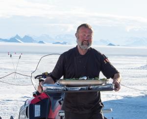 A chef standing in front of Ulvetanna Peak in Antarctica