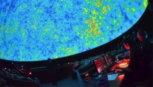 A photo of an audience sitting under the dome screen of a planetarium watching a film on the screen.