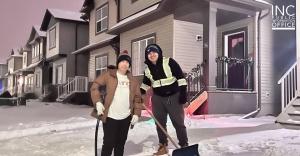 INC Giving volunteers pausing to smile as they shovel snow in a neighbour's driveway