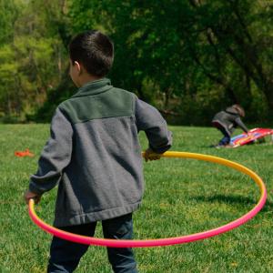 Young refugee child playing with a hula hoop during The Black Feather Foundation Youth Sports Day
