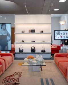 Interior of Reformation Beverly Hills retail store, with modern red velvet chairs in foreground, atop a rug with a tiger print. Handbags and shoes on shelves in background.