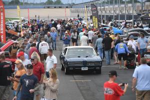 Vintage cars surrounded by people at the Speedway