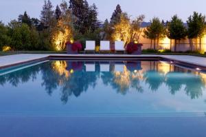 pool at dusk with landscape lighting and lounge chairs