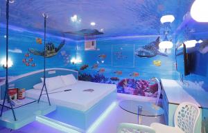 A photo of the Oceanarium Room at Hotel Sogo, featuring a bed with an ocean-themed decor including murals of fish, turtles, and coral reefs, creating an immersive underwater experience.