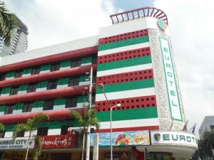 A photo of the Eurotel building in the Philippines, featuring colorful red and green stripes and various commercial establishments at the ground level.