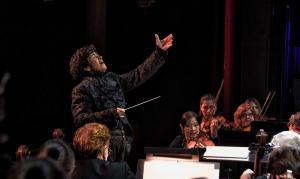 Image of a woman conducting orchestra musicians