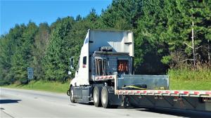 Semi truck traveling on I75 in Ohio and there is a sign with the speed limit of 65 miles per hour.