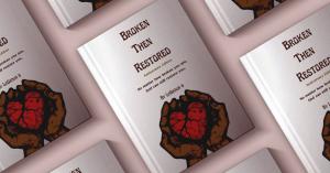 Multiple copies of LaShaun B’s book “Broken Then Restored” are displayed, featuring a cover with an illustration of hands holding a broken heart, symbolizing the journey from brokenness to restoration.