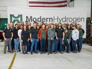 A group of 50 Modern Hydrogen employees posing for a photo with Bill Gates in the center. On either side of Bill Gates are the two co-founders, and next to the CEO is CFO Amir Moftakhar in his black Modern Hydrogen Shirt. They're standing in front of an e