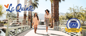 Two women stroll across a bridge lined with palm trees, enjoying a sunny day in a tropical setting.