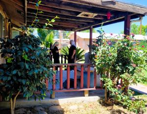 two sisters standing talking on a wooden porch with rose bushes in the foreground