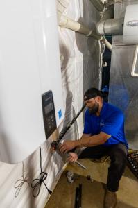 J. Blanton Plumbing technician conducting a water heater flush and maintenance service, showcasing the benefits of the No Drip Club and professional plumbing services.