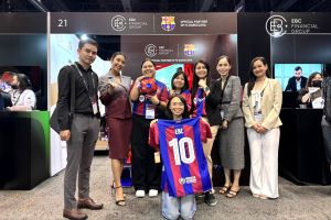 EBC Financial Group team members and attendees pose together at the iFX Expo Asia 2024 in Bangkok, displaying co-branded FC Barcelona merchandise.