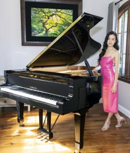 Miist the singer standing by her piano.