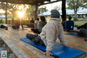 a group of people doing yoga on a wooden deck outdoors during a wellness retreat